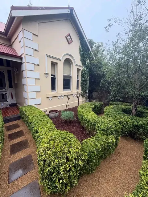 Trimmed hedges in front of a heritage home